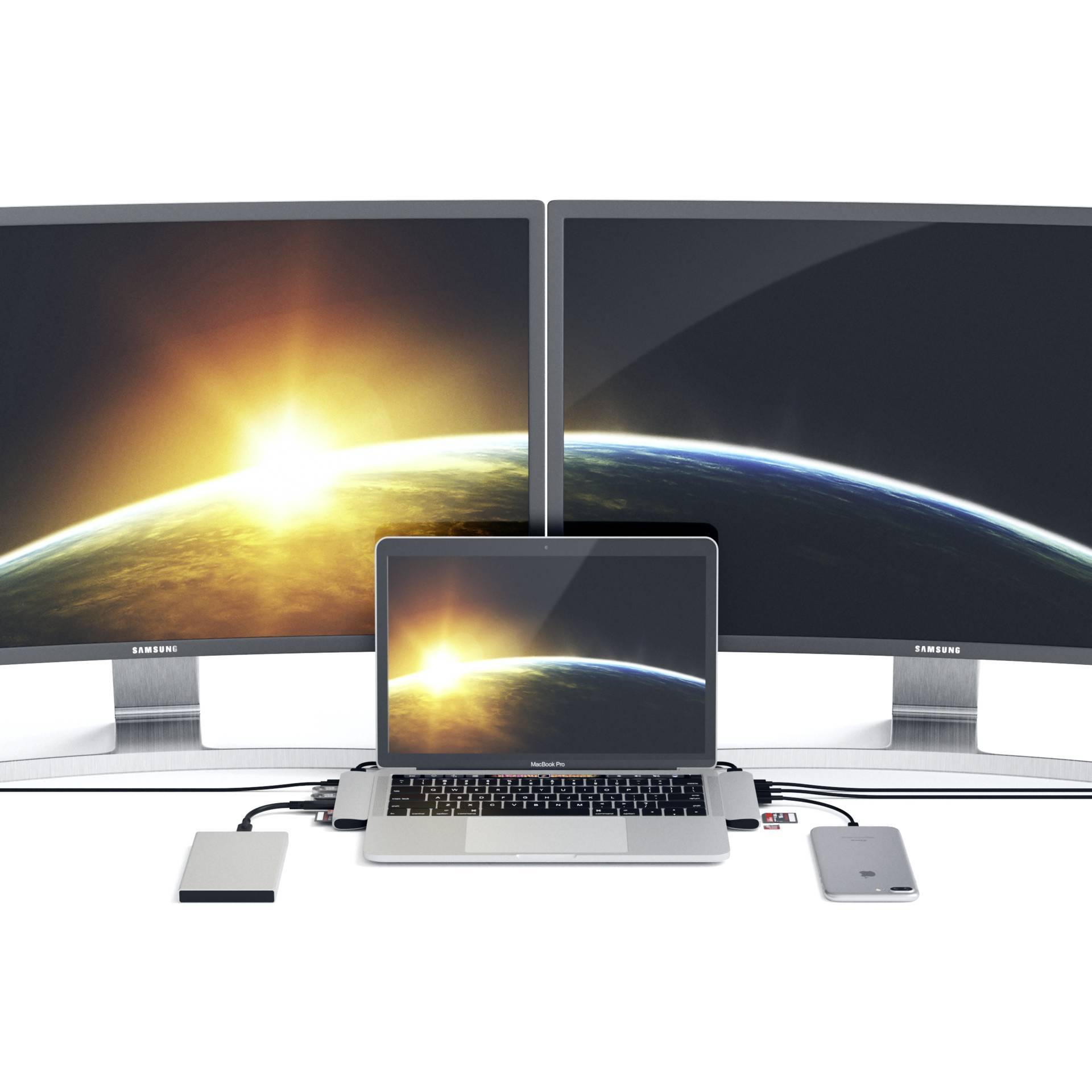 Laptop z dwoma podłączonymi monitorami wyświetlającymi ten sam kosmiczny tapeta w tle; obok różne gadżety.