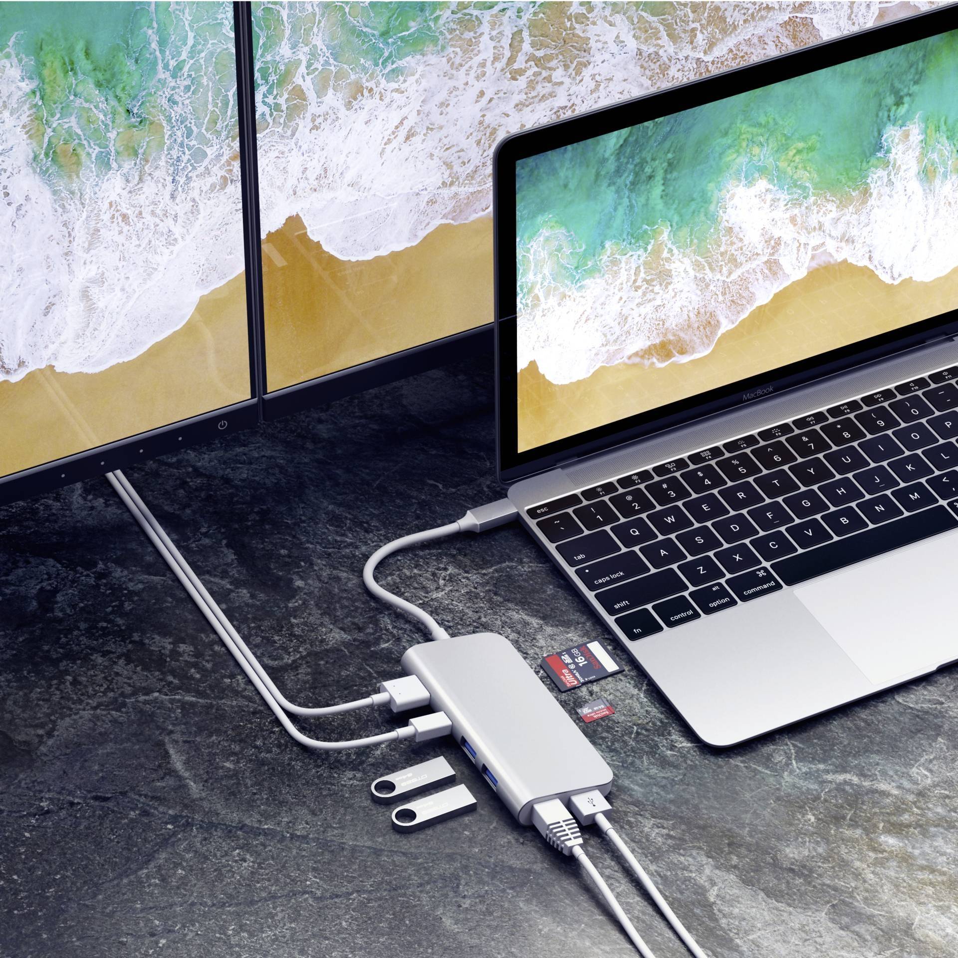 Laptop jest podłączony do koncentratora USB-C, który oferuje wiele portów do podłączenia pendrive'ów, karty SD oraz złącza HDMI, rozszerzając tym samym możliwości pracy.