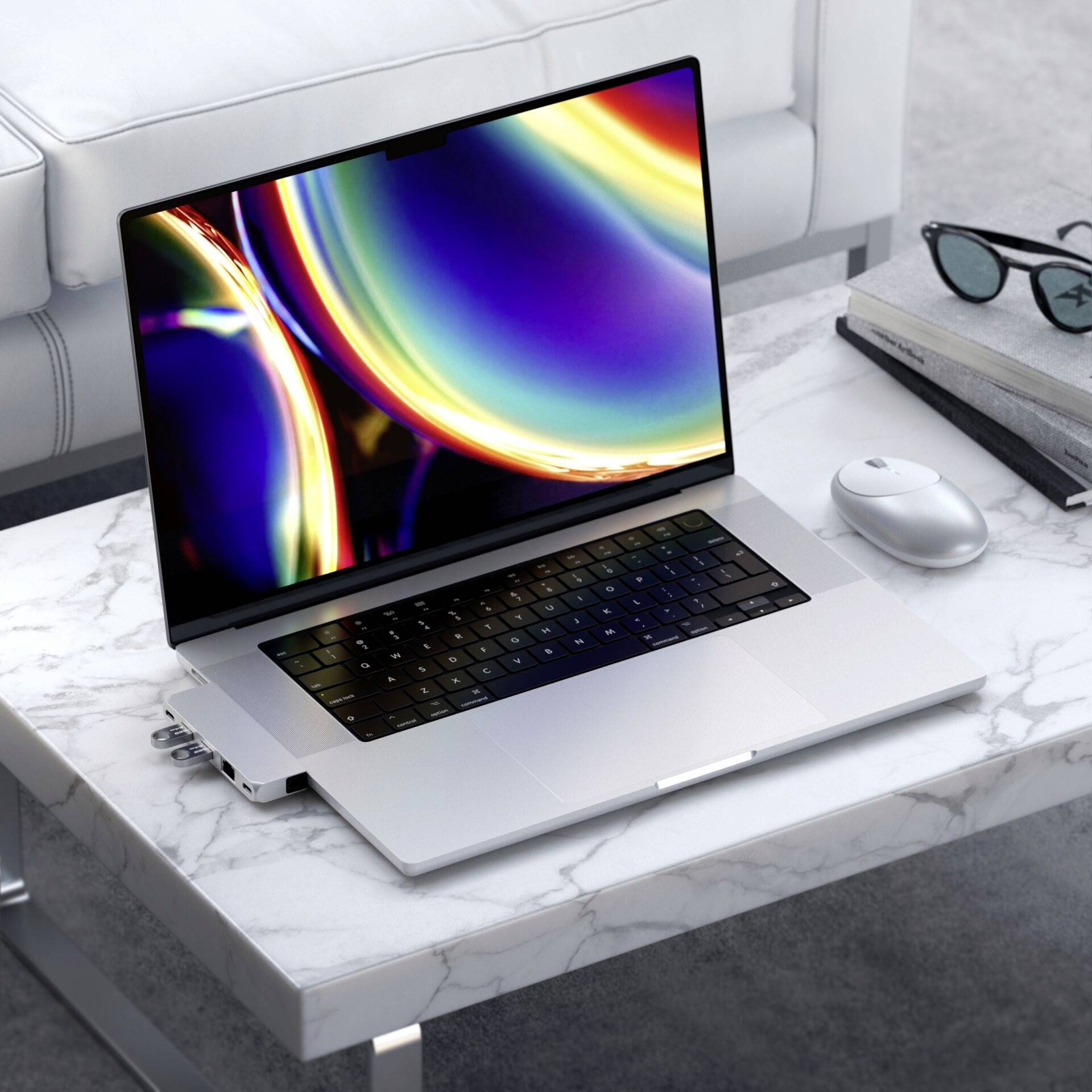 Laptop z kolorowym, abstrakcyjnym ekranem stoi na marmurowym stoliku kawowym obok bezprzewodowej myszy i notesu.