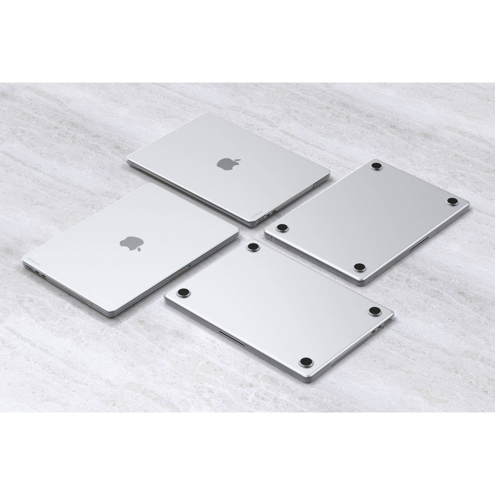 Cztery srebrne laptopy, częściowo otwarte i zamknięte, na jasnym kamiennym podłożu. Dwa pokazują górną powierzchnię z logo, dwa dolną powierzchnię.