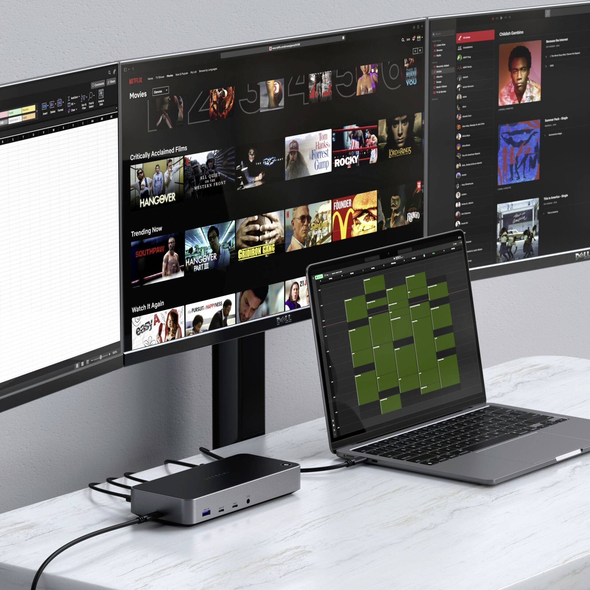 Biurko z wieloma monitorami wyświetla różne treści cyfrowe, takie jak filmy i muzyka. Laptop pokazuje kalendarz.