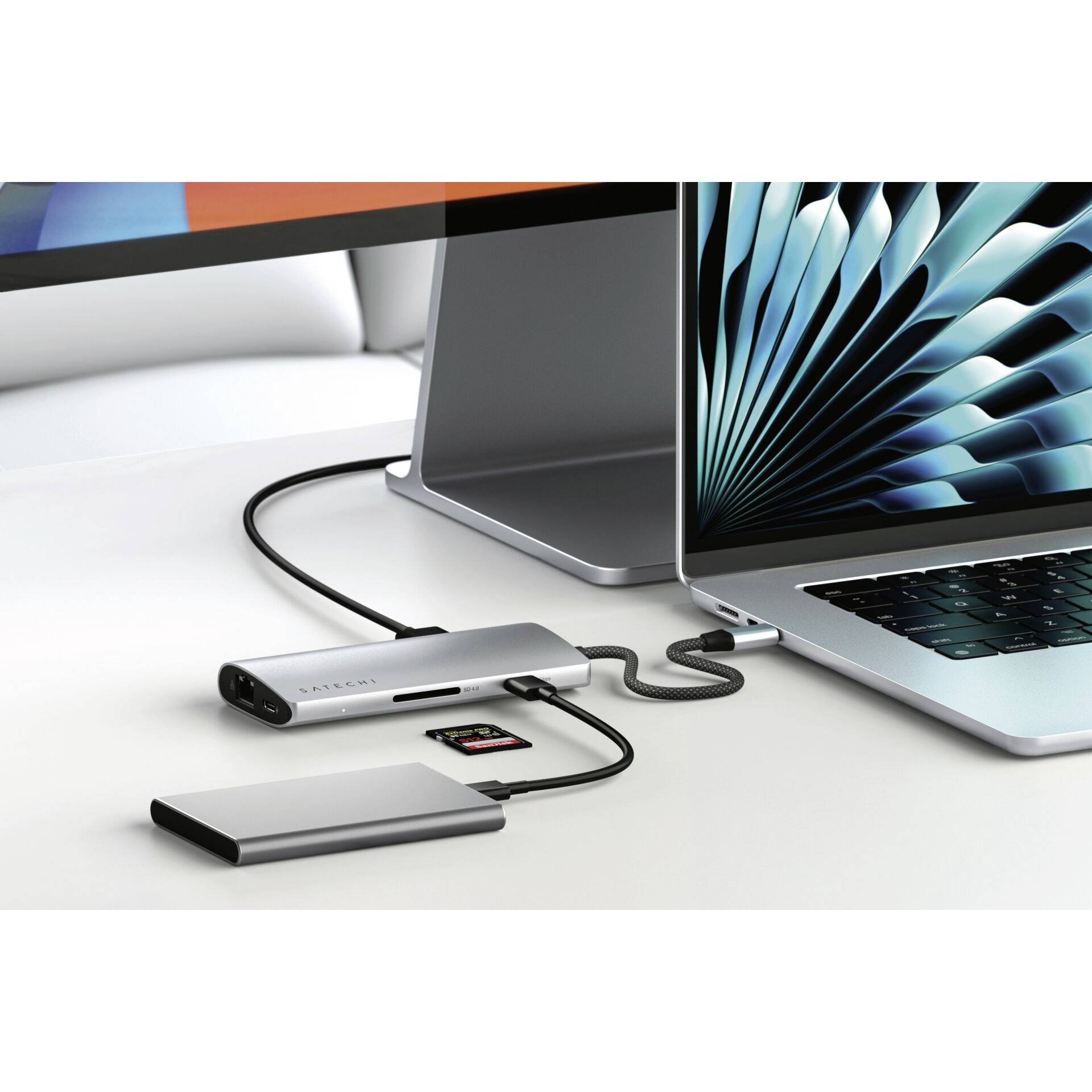 Laptop jest podłączony do stacji dokującej USB-C, która oferuje wiele portów, w tym złącza USB i gniazda kart SD.