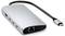 Srebrny hub USB-C z wieloma portami, w tym HDMI, USB-A, Ethernet i USB-C. Łączy różne urządzenia.