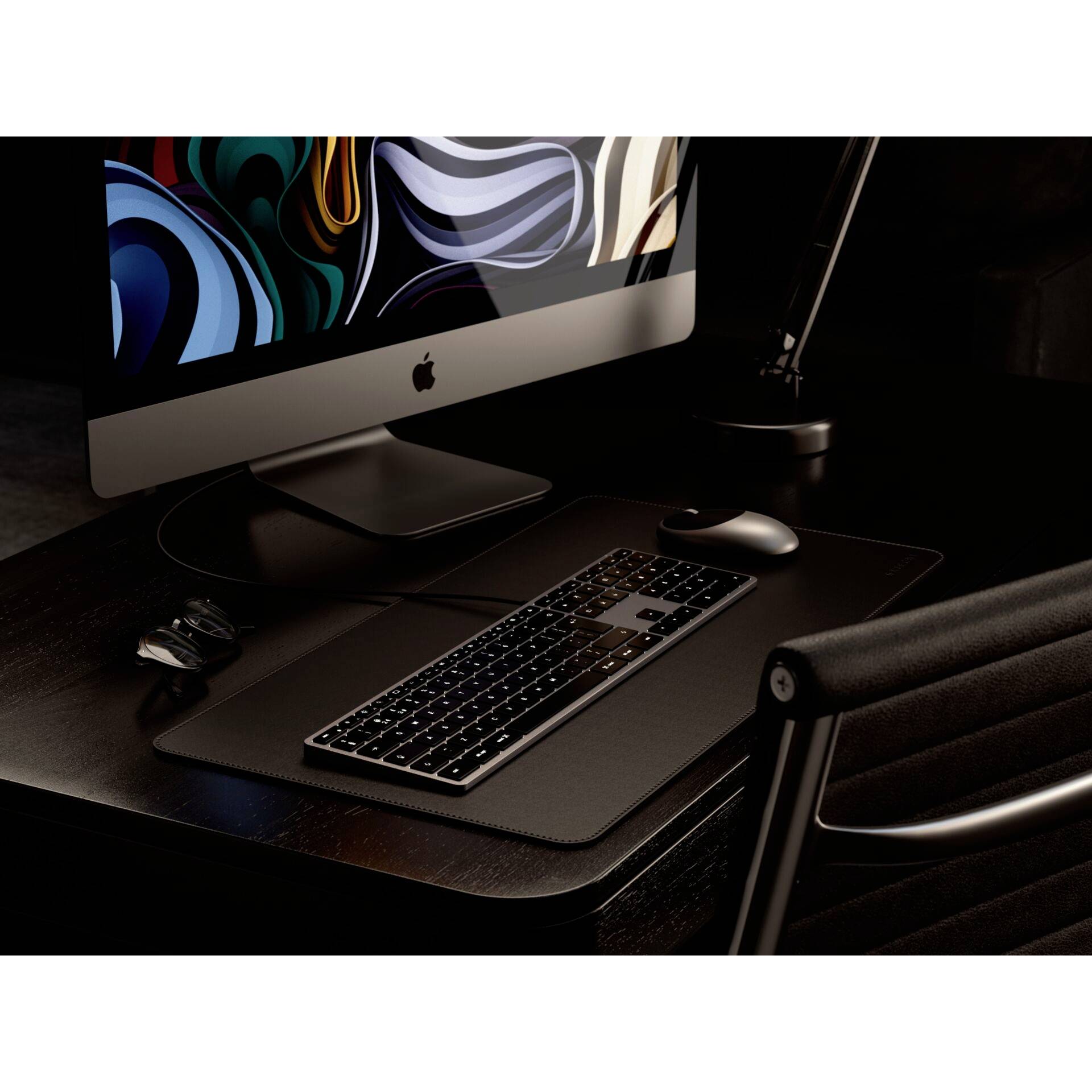 Nowoczesne biurko z dużym ekranem komputerowym wyświetlającym abstrakcyjną sztukę. Klawiatura i mysz leżą na ciemnym podłożu.