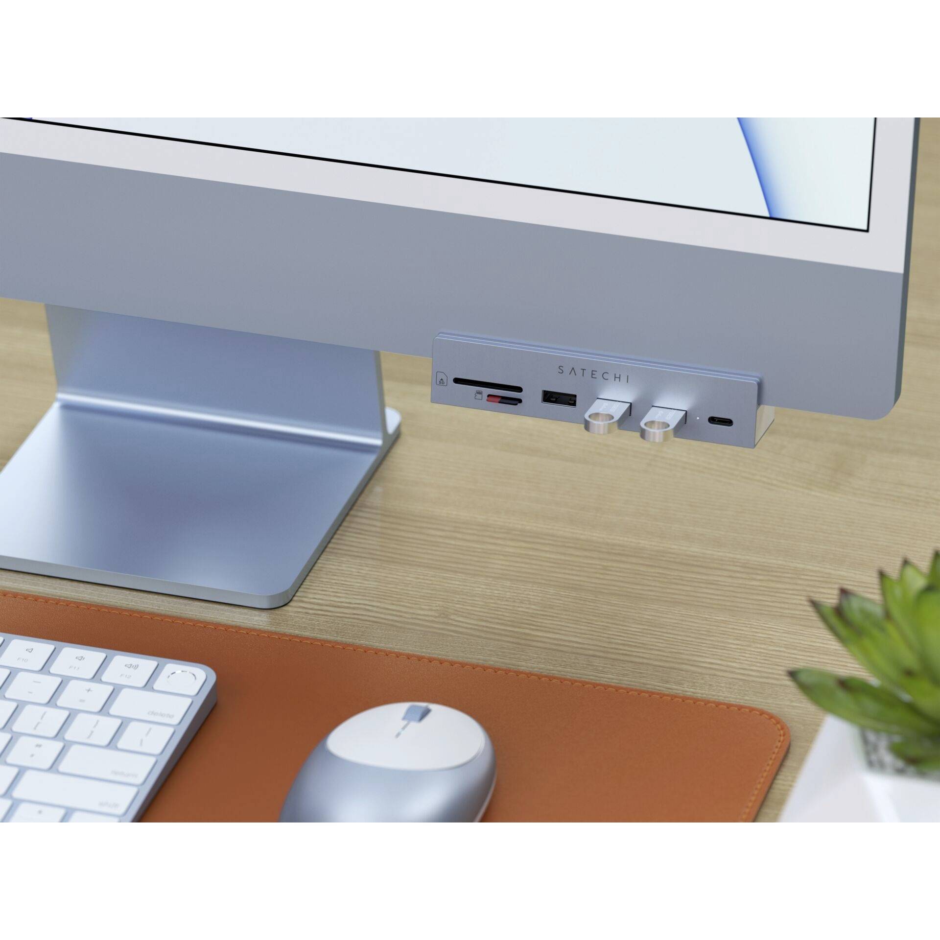 Na biurku stoi monitor komputerowy z podłączonym hubem USB. Obok niego umieszczona jest klawiatura i mysz.