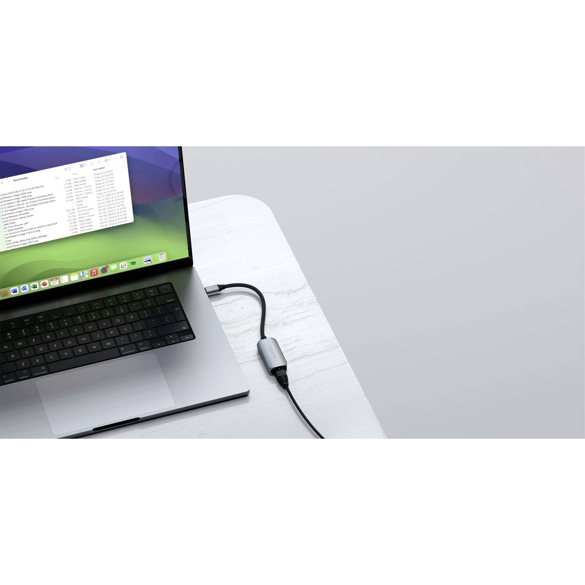 Laptop z otwartym oknem poczty elektronicznej, podłączony kablem USB-C do stołu.