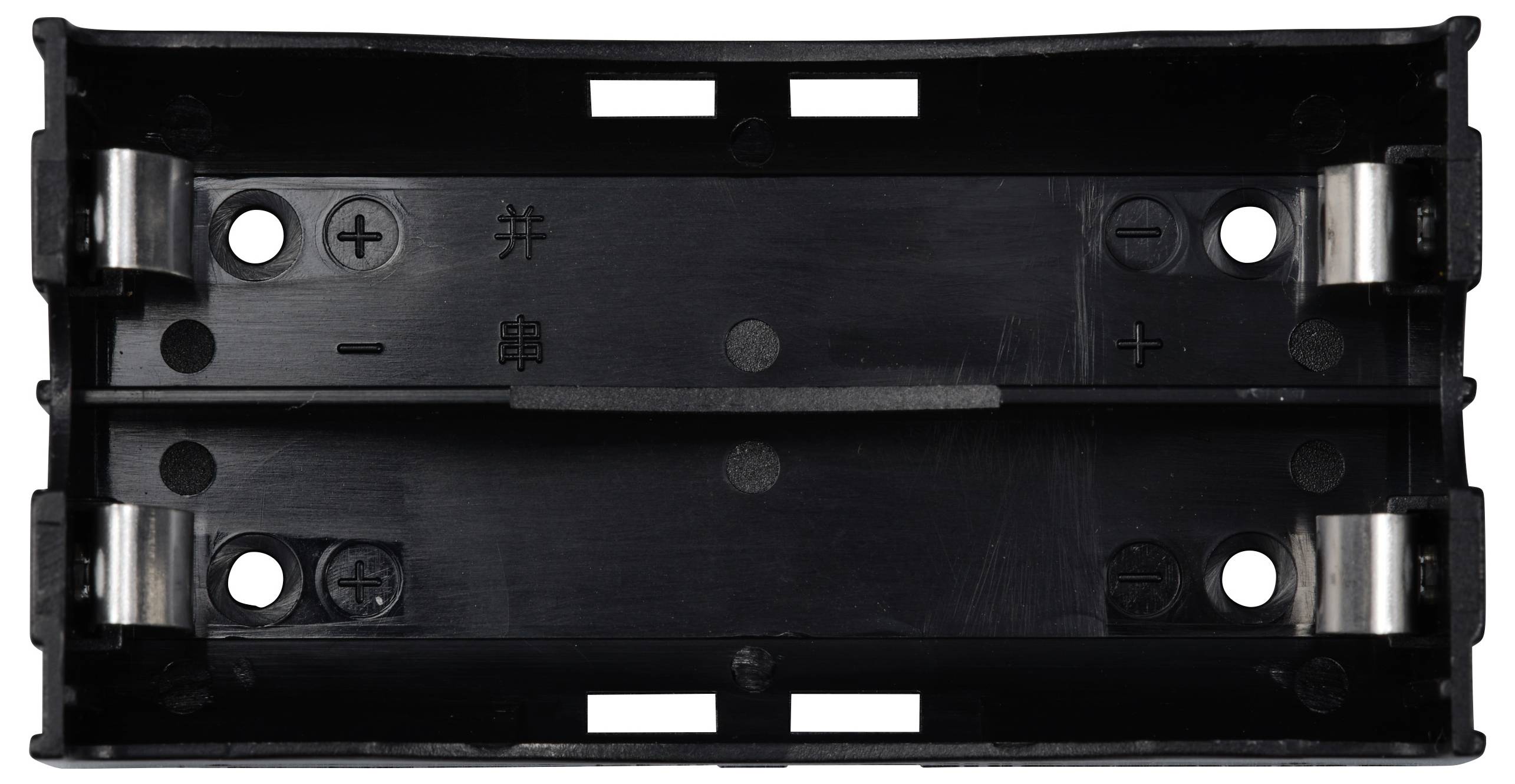 Czarna obudowa na dwie baterie AA, z zaciskami do podłączenia biegunów dodatniego i ujemnego, widoczne punkty mocowania śrub.