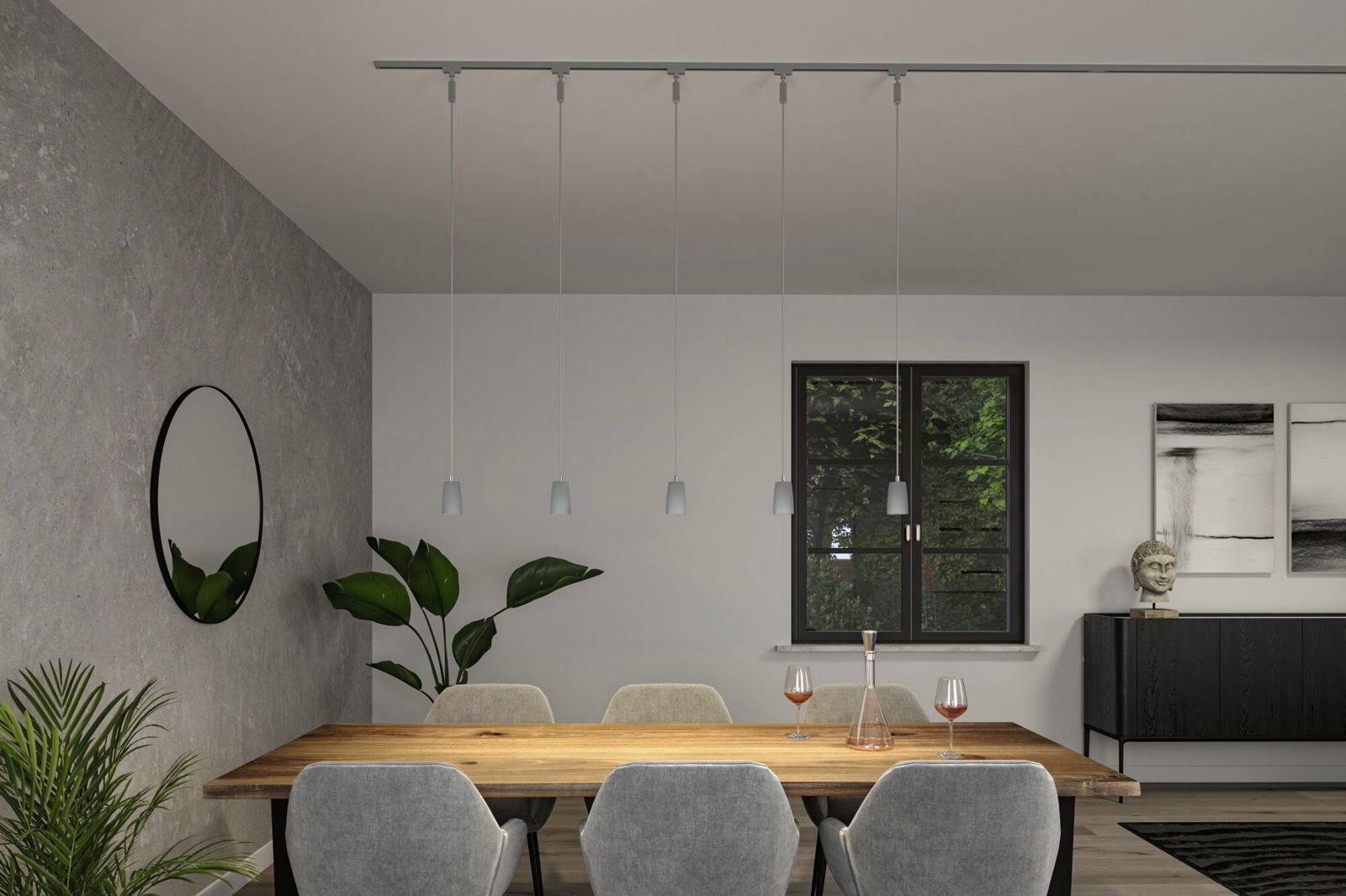 Jadalnia z drewnianym stołem, otoczona szarymi krzesłami, z nowoczesną lampą wiszącą sufitową i roślinami przy ścianach.