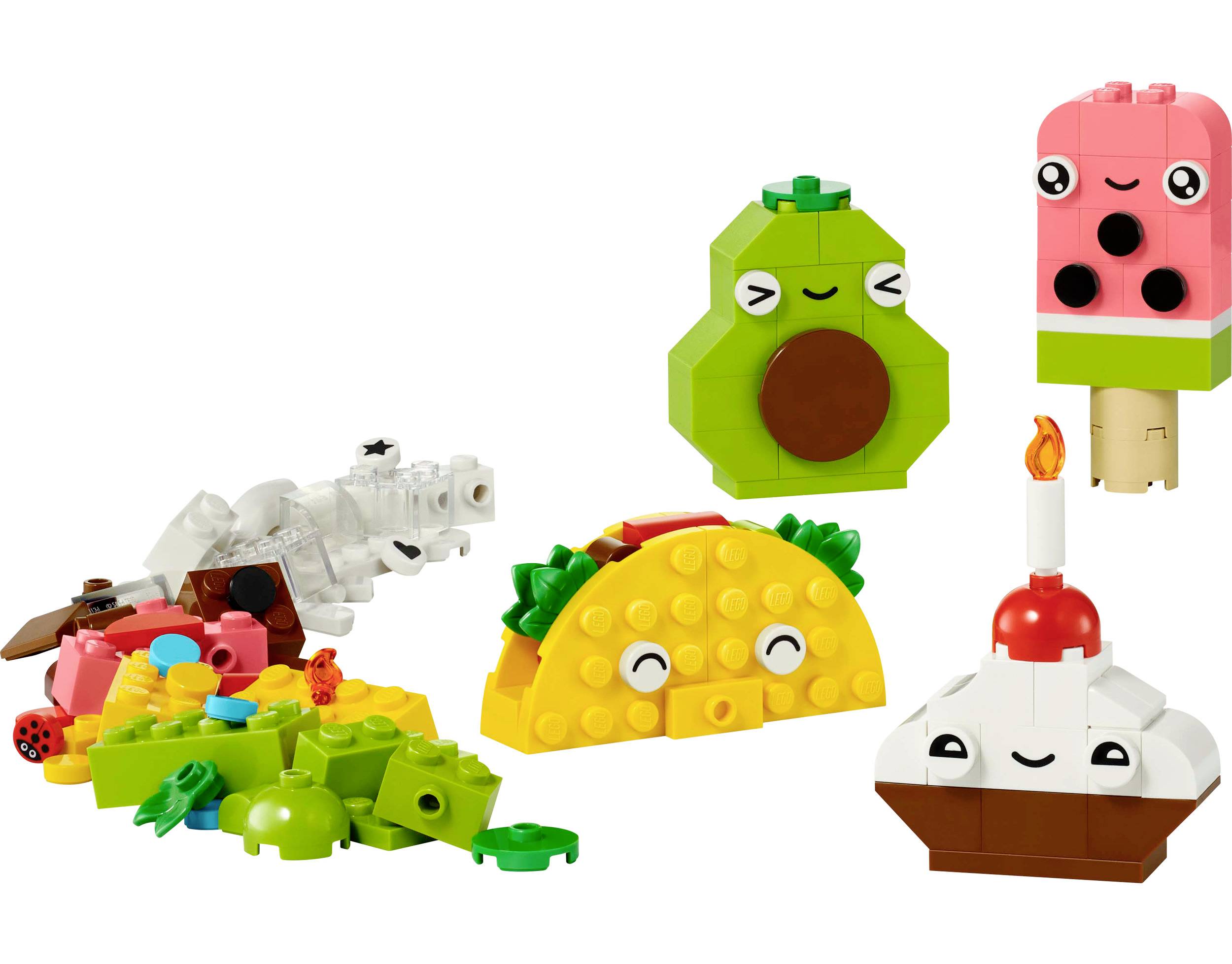 Kolorowe klocki LEGO tworzą wesołe postacie: taco, awokado, loda na patyku oraz statek w kształcie tortu ze świeczką, otoczone elementami budowlanymi.