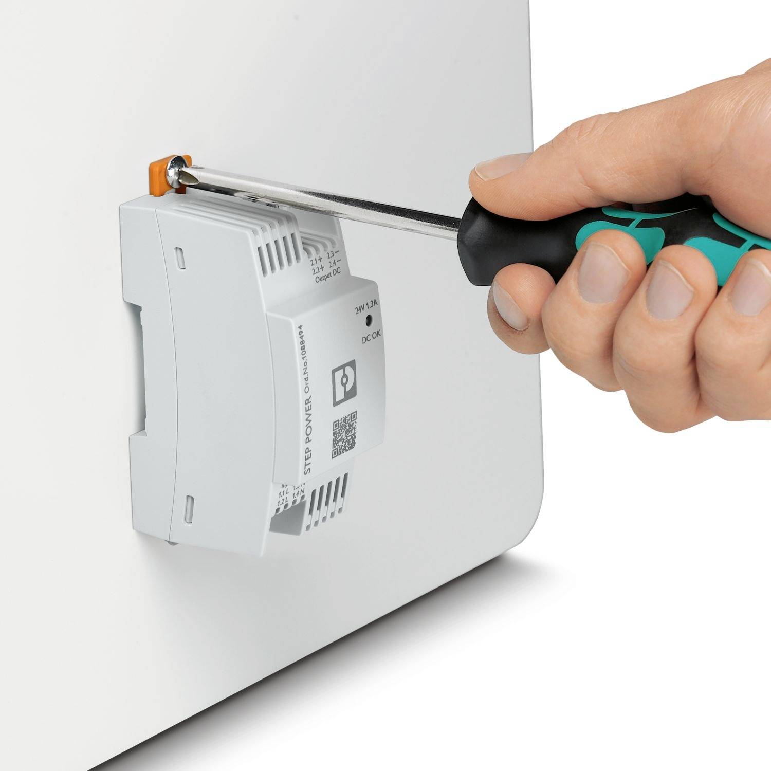 Ręka dokręca śrubę wkrętakiem w obudowie urządzenia elektrycznego.