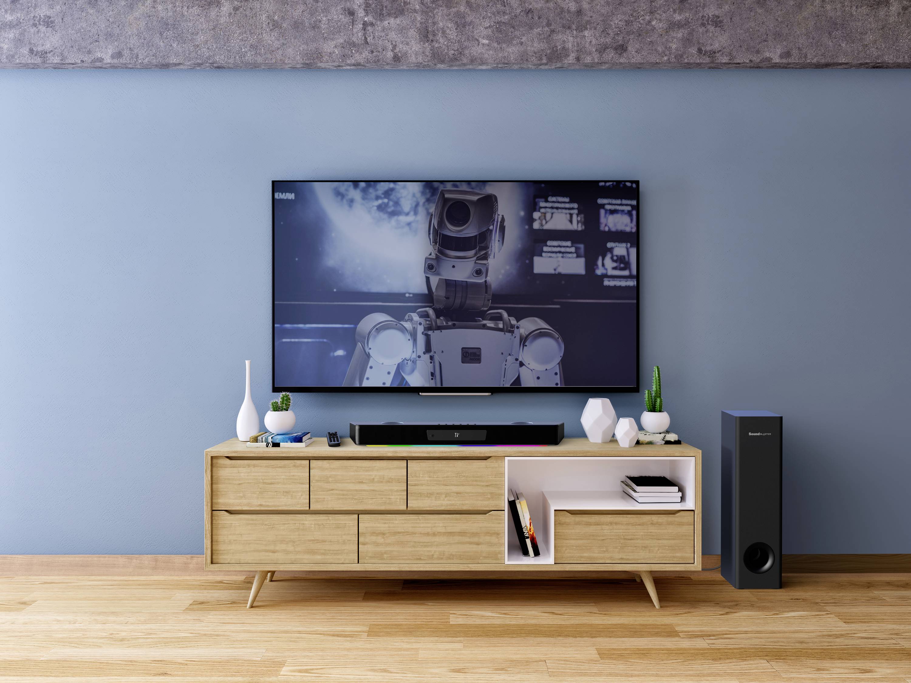 Nowoczesny telewizor stojący na drewnianej szafce wyświetla obraz przedstawiający robota w kosmosie. Obok niego znajdują się głośniki i małe artykuły dekoracyjne.