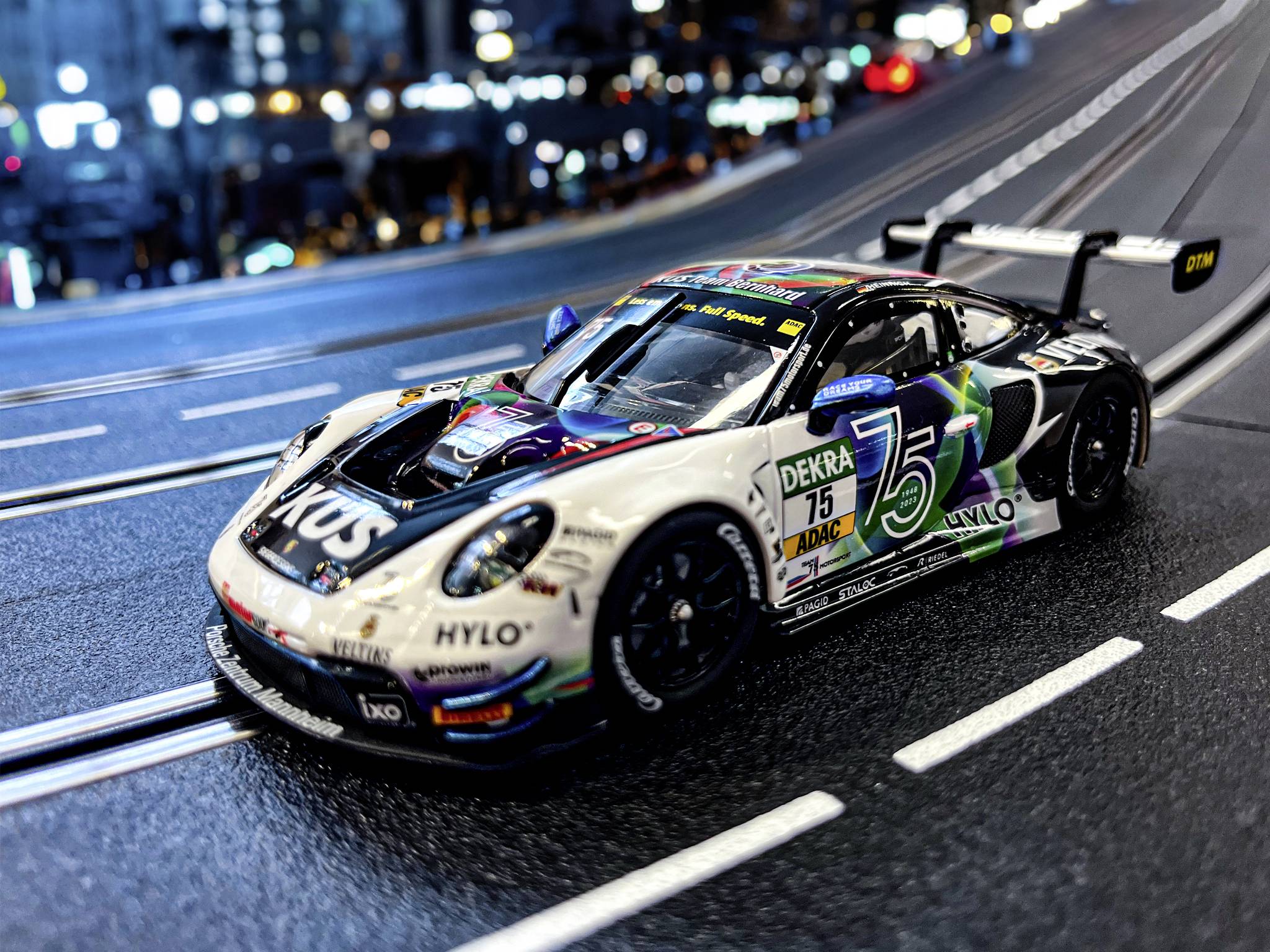 Miniaturowy model samochodu wyścigowego na symulacji toru, w tle niewyraźne światła miasta.