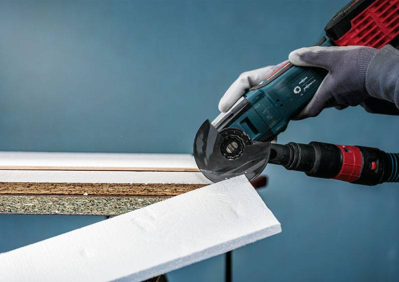 Osoba przecina grubą płytę styropianową kątnówką, demonstrując precyzyjne posługiwanie się narzędziem.