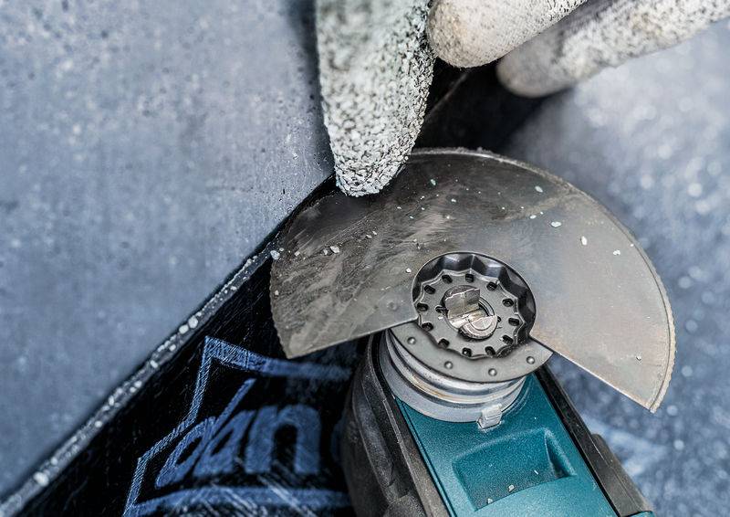 Dłoń w rękawicy ochronnej trzyma tarczę tnącą, która przecina metal. Iskry lecą, jest to sytuacja robocza.