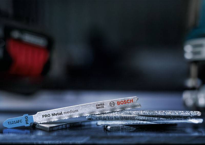 Metalowe brzeszczoty z napisem 'PRO Metal medium' oraz logo marek Bosch i Swiss Made, leżące na stole.