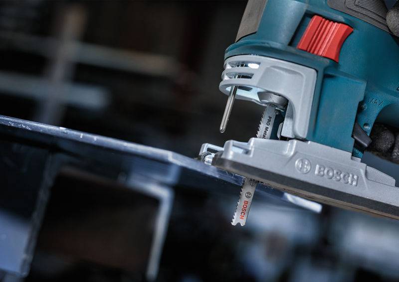 Elektryczna wyrzynarka przecina kawałek metalu. Urządzenie jest produkowane przez Boscha i wykazuje się precyzyjnym działaniem.