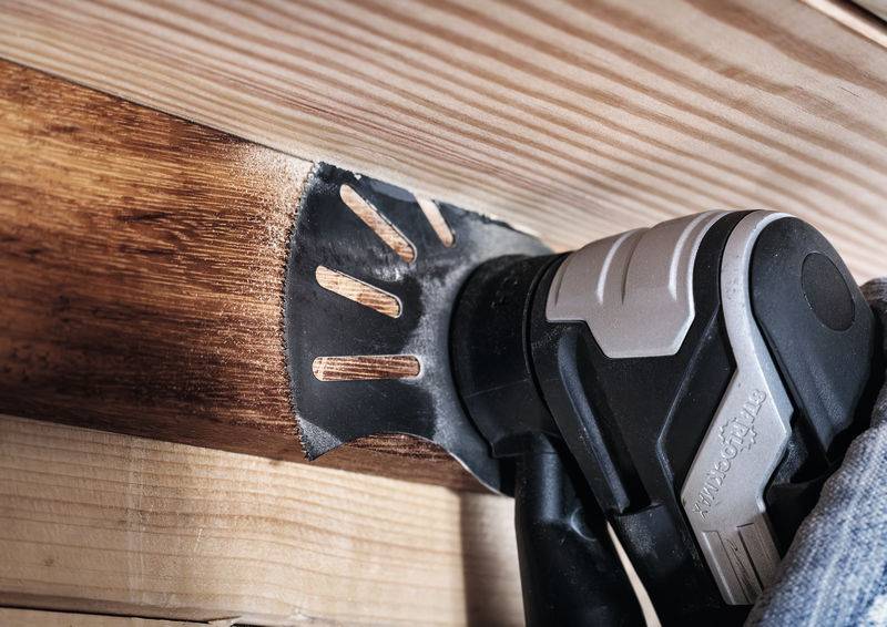 Elektryczna szlifierka jest używana na desce drewnianej. Papier ścierny wygładza powierzchnię drewna.