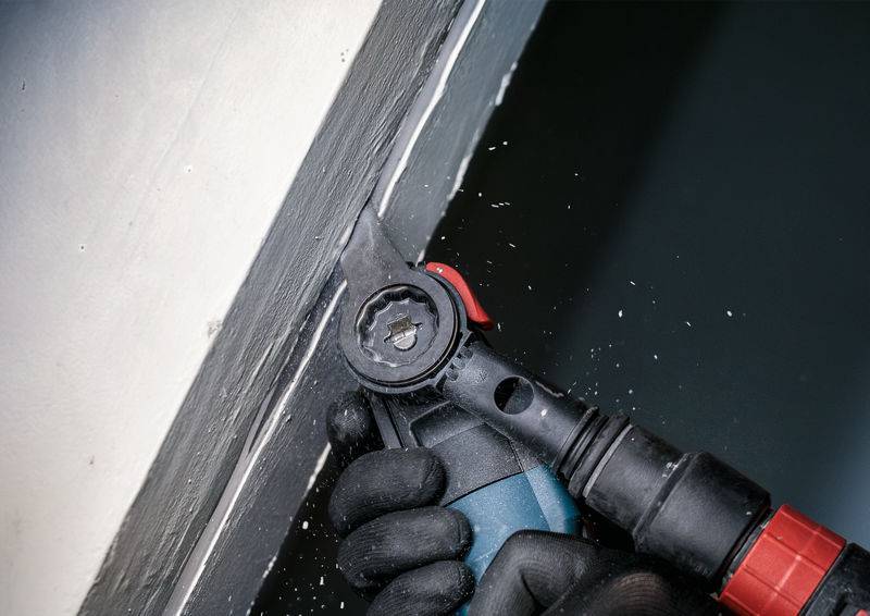 Osoba czyści spoinę okienną za pomocą elektronarzędzia. Podczas pracy powstają małe odpryski materiału.