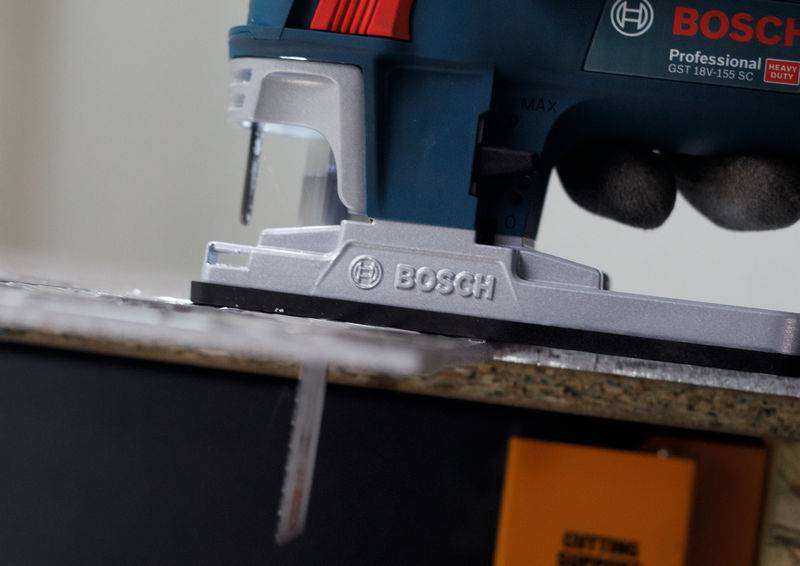 Piła Bosch przecina deskę. Zbliżenie ukazuje piłę w akcji z widocznymi wiórami i wyraźnym logo marki.