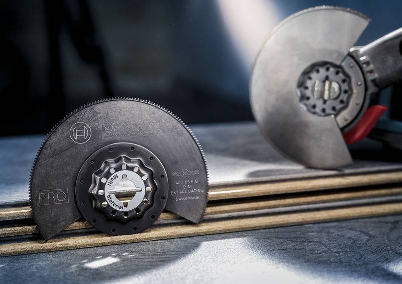 Zbliżenie na dwa ostrza piły leżące na drewnianych deskach, jedno ustawione pionowo, drugie ułożone płasko.