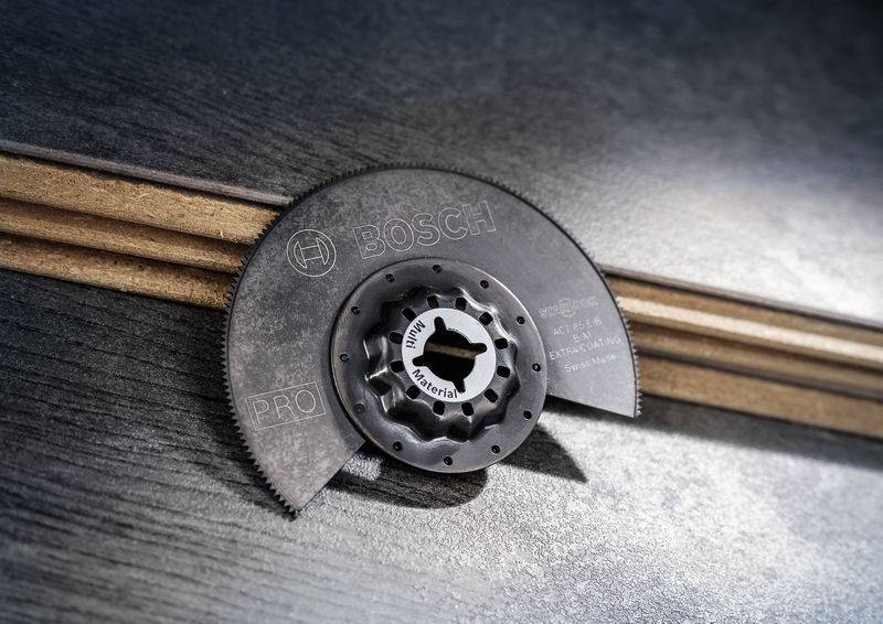 Półksiężycowaty brzeszczot firmy Bosch leży na drewnianych listwach. Tekst na brzeszczocie: 'BIM Multi Material'.