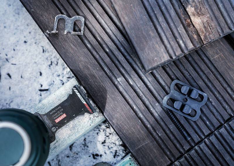 Metalowe elementy i zielony pojemnik leżą na drewnianej podłodze. Światło i cienie tworzą interesujący wzór.