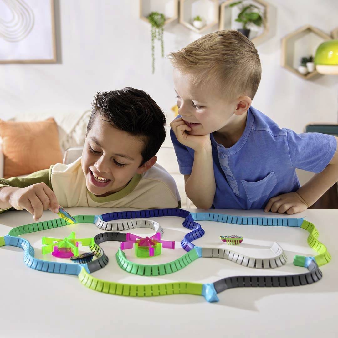 Dwoje dzieci wspólnie gra w grę planszową z kolorowymi pionkami. Wyglądają na skupione i zadowolone, wykonując swoje ruchy.