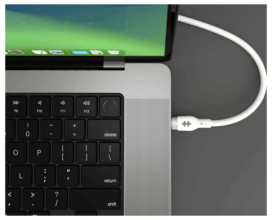 Laptop z podłączonym kablem ładującym, częściowo widoczna klawiatura, ekran z zielonym interfejsem użytkownika.