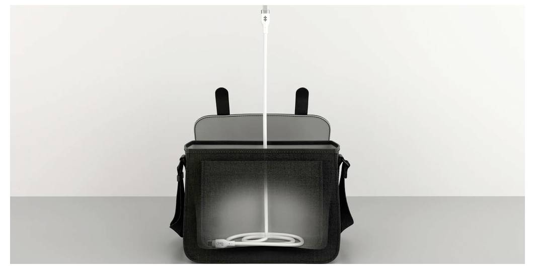 Czarna torba na szarym stole, otwarta, z wystającym białym kablem USB.