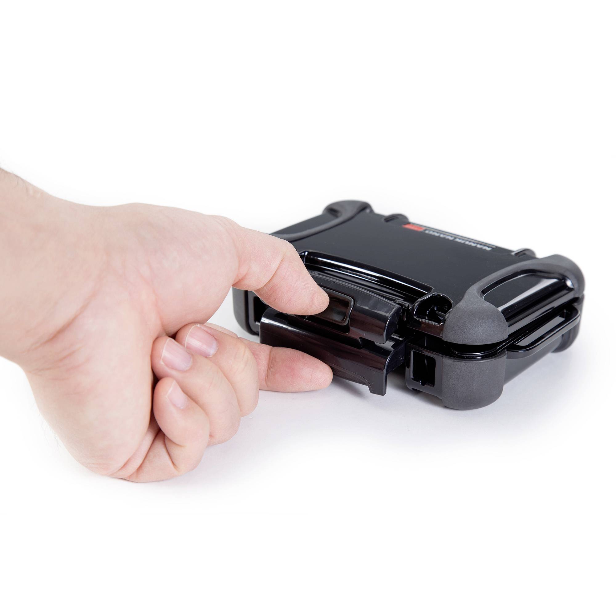 Jedna ręka naciska czarny, prostokątny mechanizm, który wygląda jak zamek lub urządzenie mocujące.