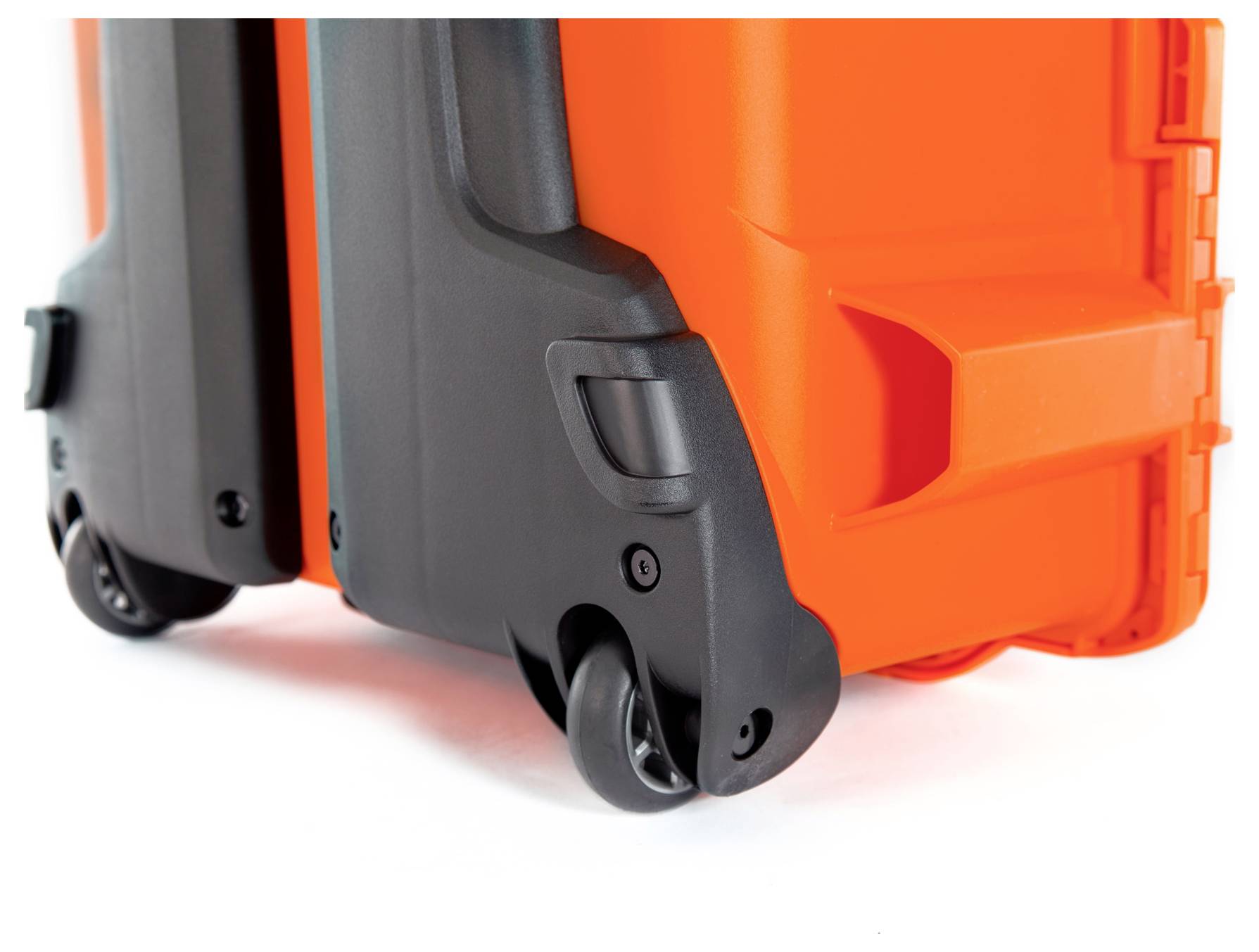 Pomarańczowa walizka z twardą skorupą z czarnymi kółkami, zbliżenie na dolne narożniki i kółka.