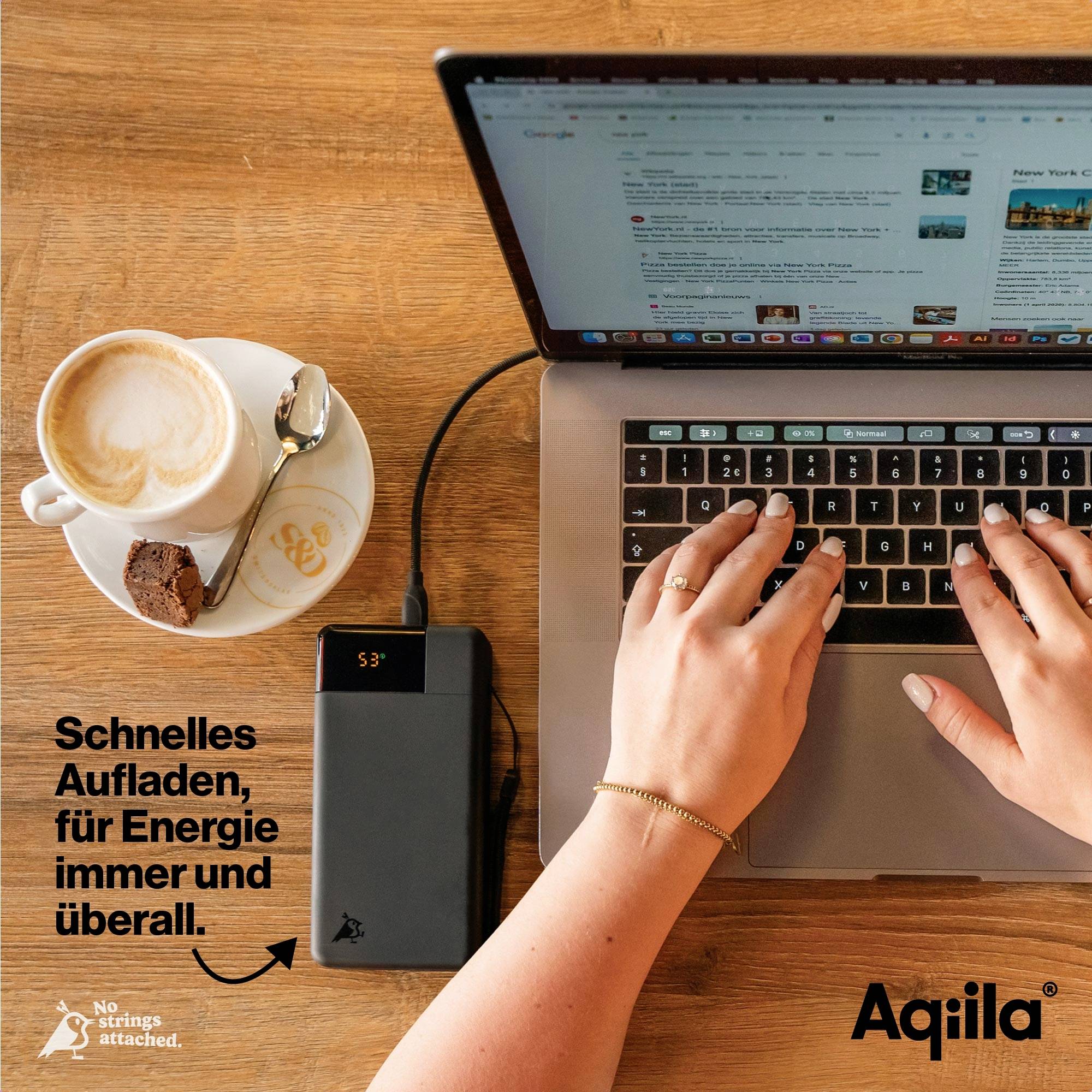 Osoba pracuje na laptopie podłączonym do power banku. Obok na stole stoją filiżanka kawy i ciastka. Tekst na obrazie: 'Szybkie ładowanie, wszędzie.'