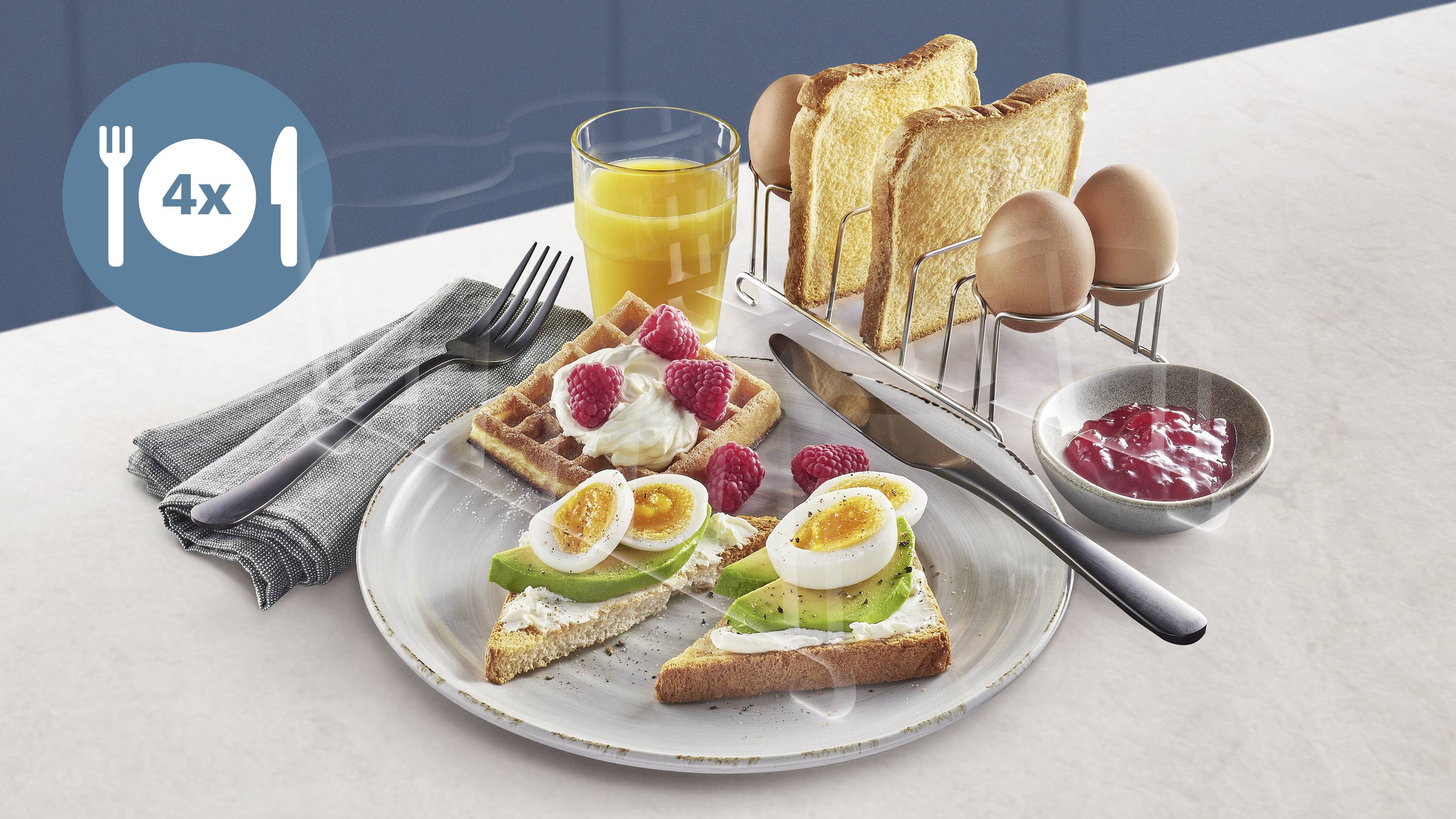 Stół śniadaniowy z tostami, jajkami, goframi, malinami, tostami z awokado i sokiem pomarańczowym. Obok sztućce i dżem.