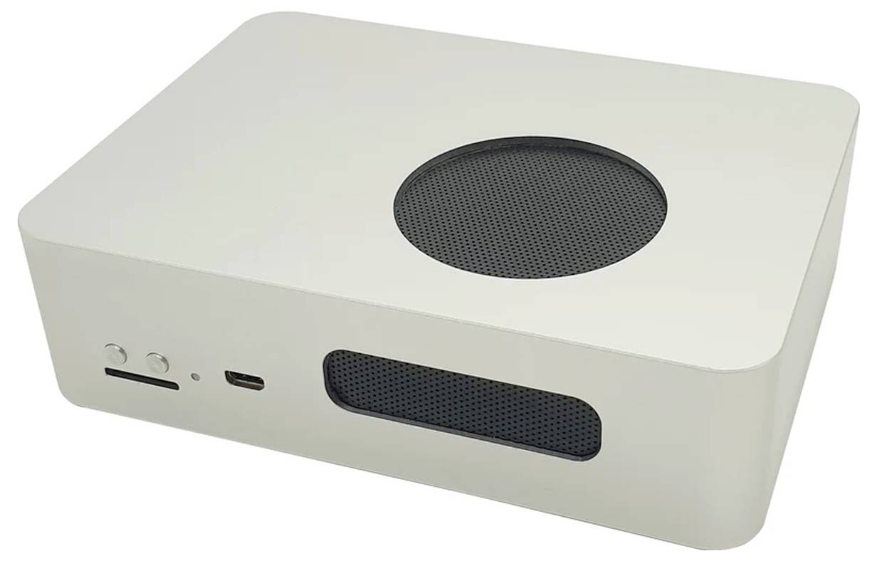 Mały, prostokątny, biały komputer z zaokrąglonymi rogami i kratką wentylacyjną na górnej powierzchni. Z przodu widoczne są złącza.