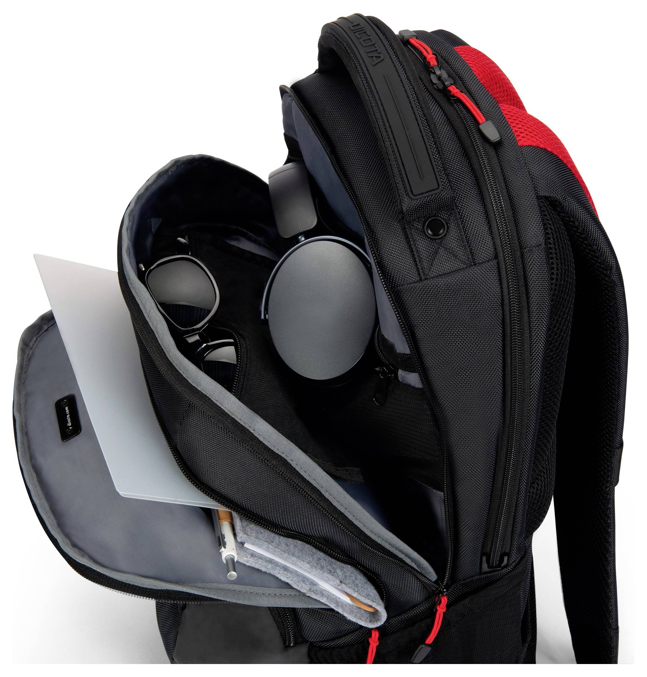 Otwarty, czarny plecak wewnątrz ujawnia laptopa, okulary przeciwsłoneczne, słuchawki i długopis.