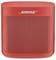 Czerwony głośnik Bluetooth firmy Bose. Kompaktowa, prostokątna forma z zaokrąglonymi rogami i perforowaną kratką z przodu.