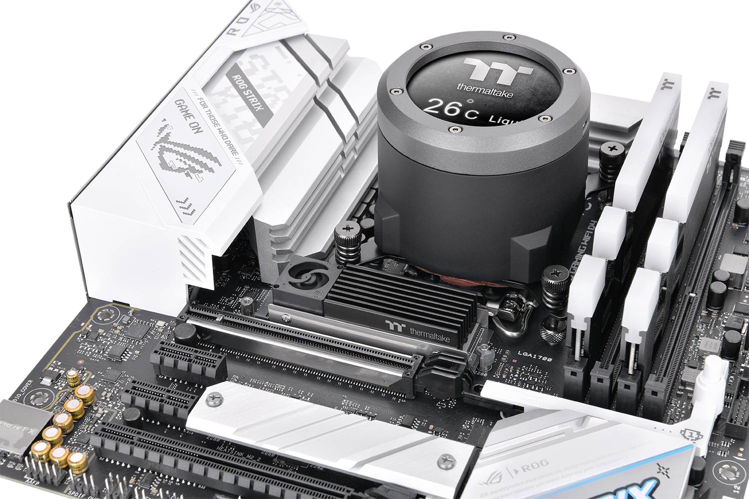 Płyta główna z systemem chłodzenia i gniazdami pamięci, logo Thermaltake na chłodnicy, kompatybilna z procesorami Intel, białe akcenty.