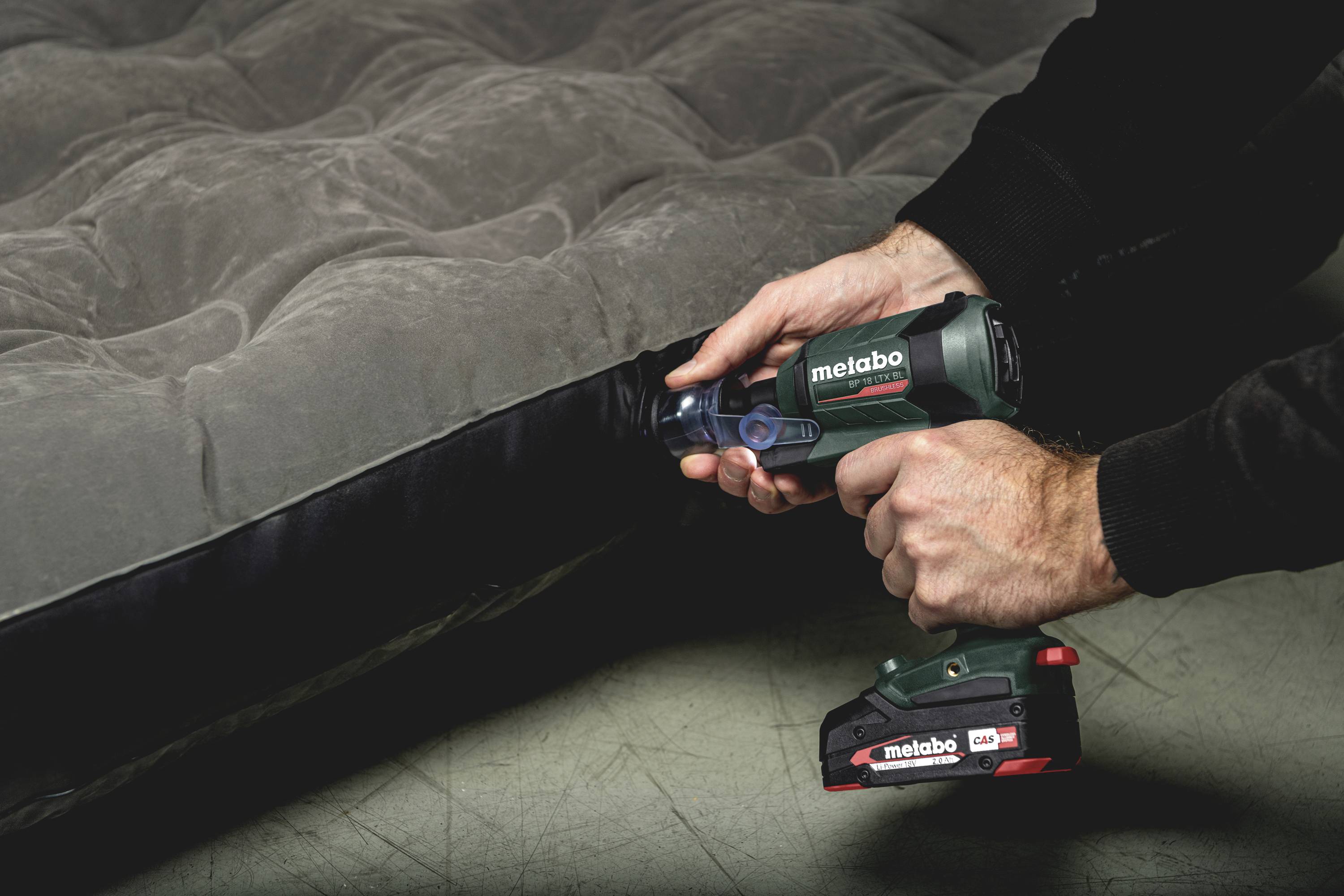 Mężczyzna pompuje materac dmuchany elektrycznym kompresorem.