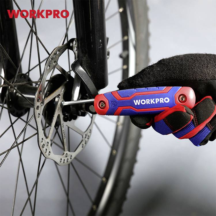 Ręka trzyma czerwono-niebieskie multitool marki Workpro i dokręca śrubę w systemie hamulcowym roweru.