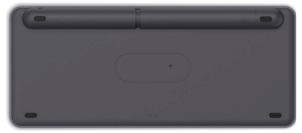 Spód czarnego urządzenia z czterema antypoślizgowymi stopkami w narożnikach oraz owalną osłoną pośrodku.