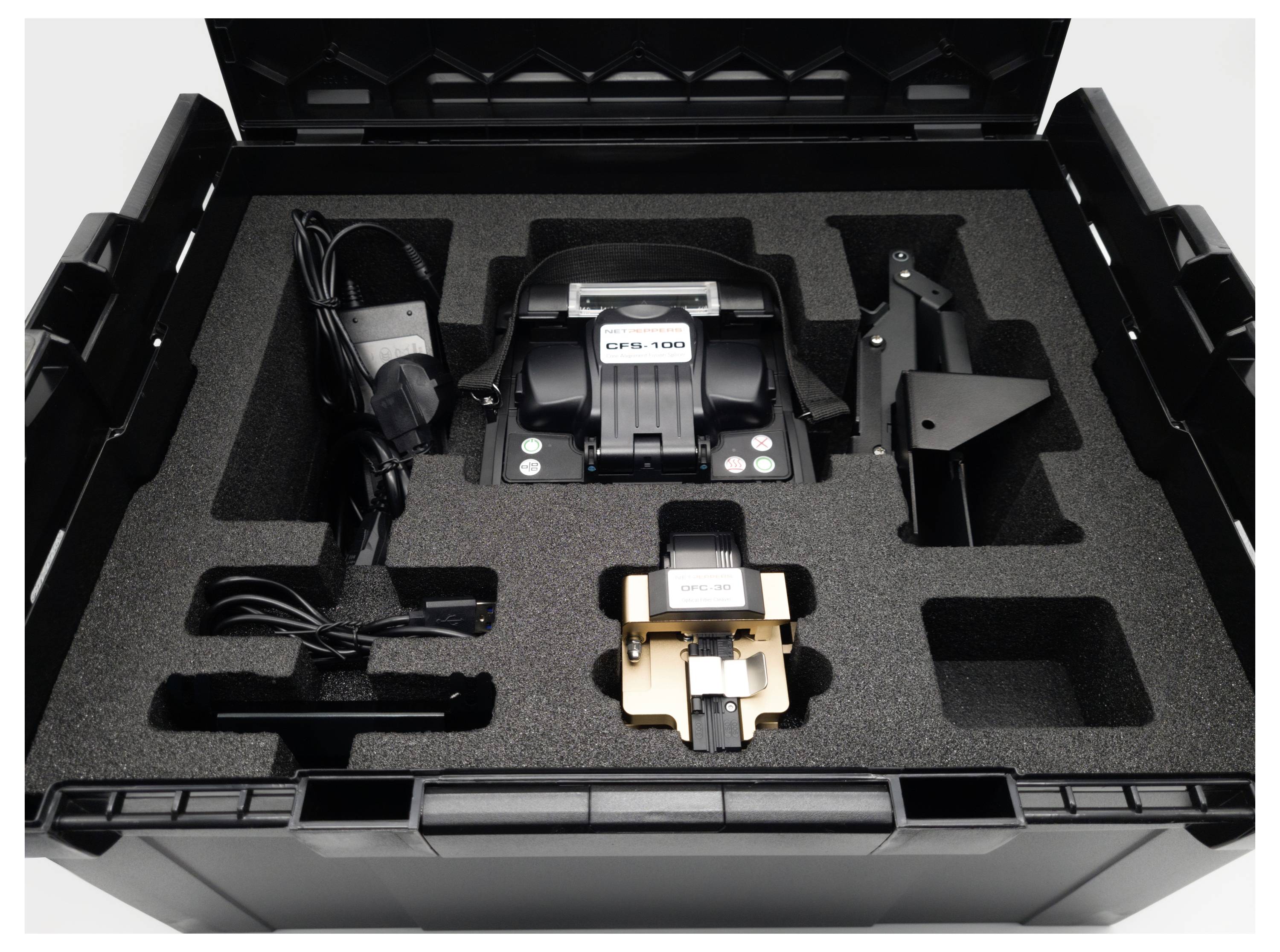 Otwarty czarny kufer z elektronicznym urządzeniem i częściami akcesoriów, bezpiecznie umieszczonymi w piankowych przegródkach.