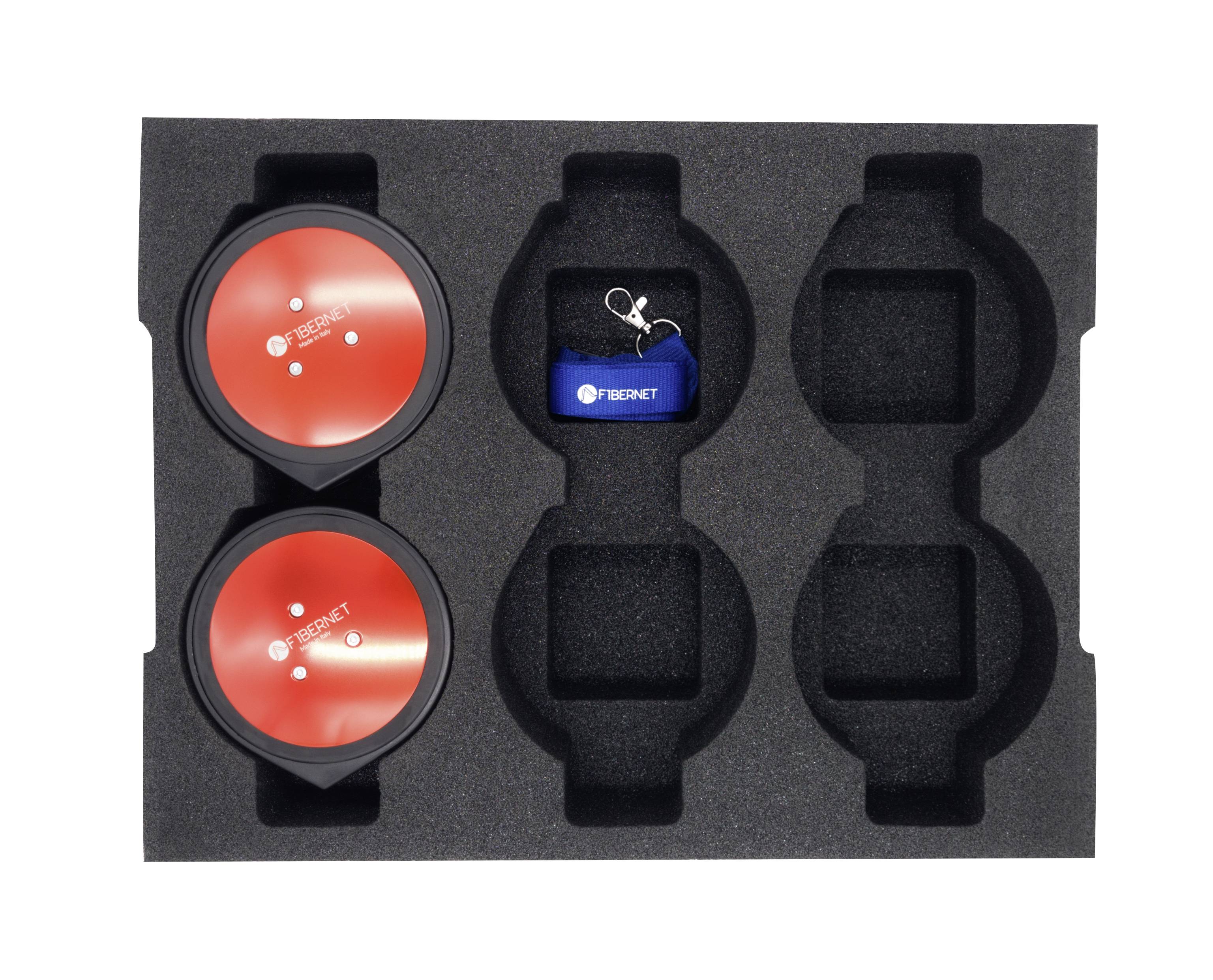 Dwie czerwone, okrągłe osłony oraz niebieski pendrive z kluczem w czarnym uchwycie z pianki, będące częścią zestawu technicznego.