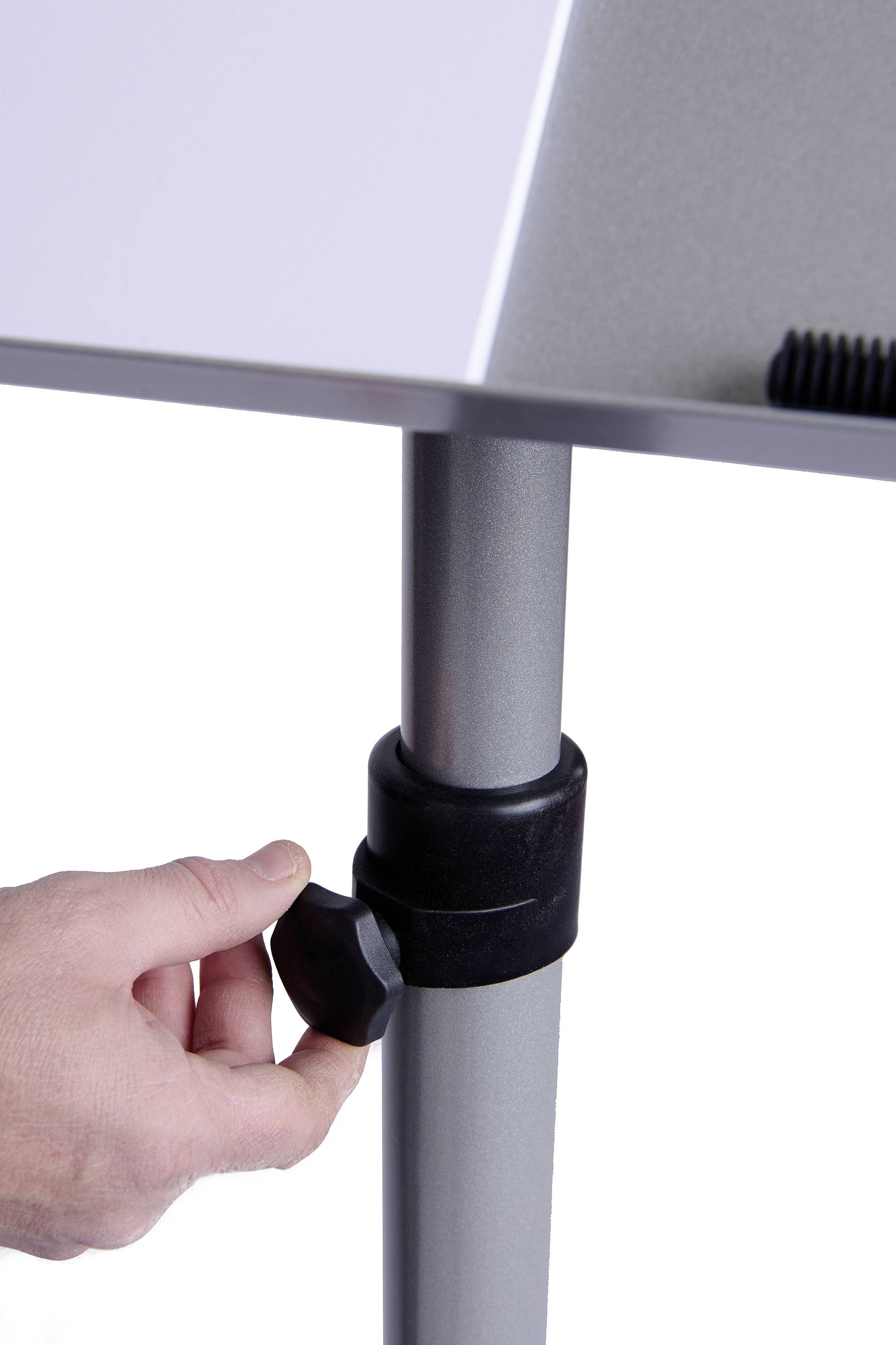 Dłoń obraca czarny gałek, aby wyregulować wysokość srebrnej nogi stołowej.