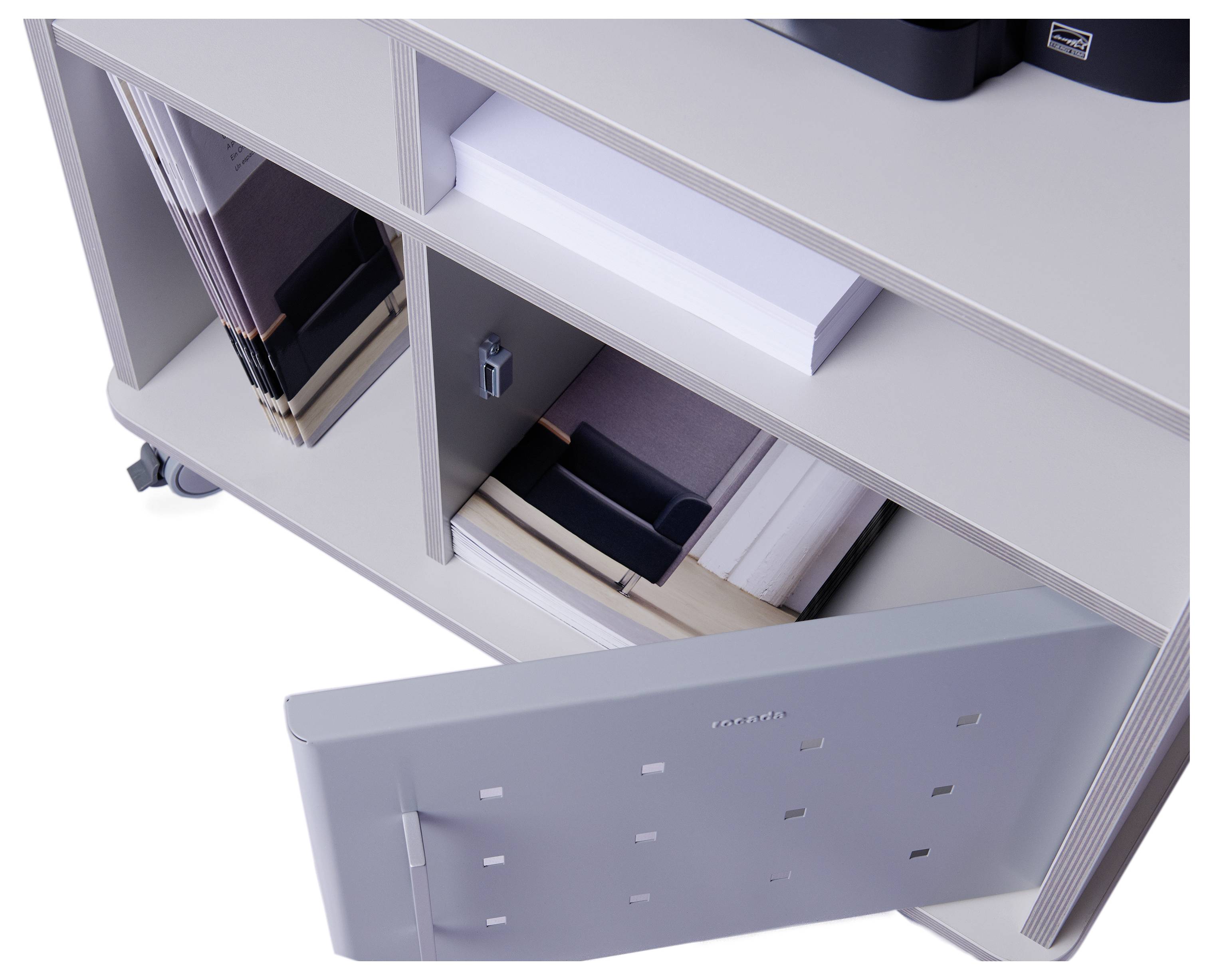 Szara, mobilna szafka regałowa z odkrytymi przegrodami. Niektóre półki zawierają segregatory, jedna jest wypełniona dokumentami, a drzwiczki jednej z przegród są otwarte.