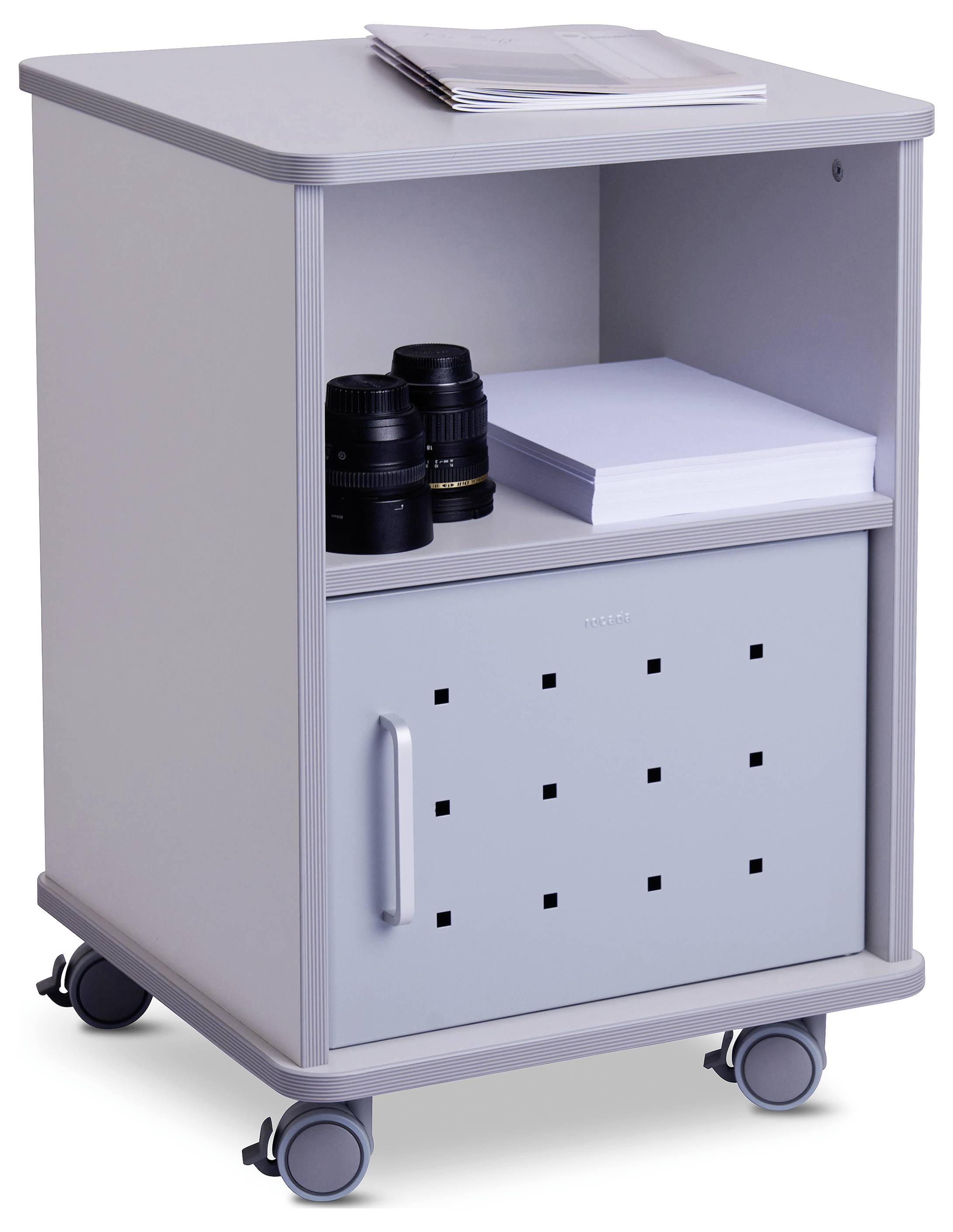 Szary kontener na kółkach z czterema kółkami. Na górze papier i dwa obiektywy aparatu, poniżej przegródka z kolejnym papierem i zamkniętymi drzwiczkami.