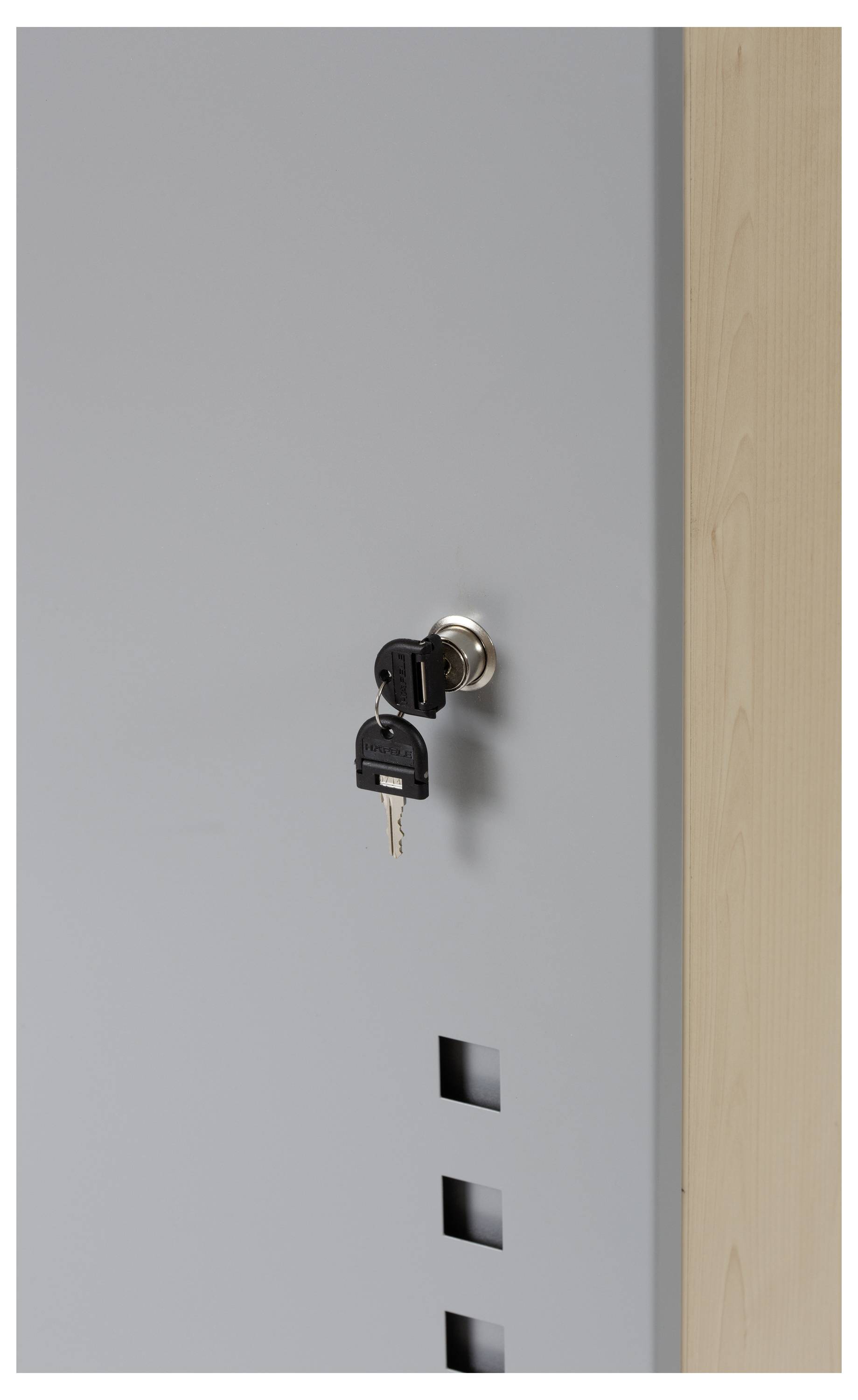 Szara szafa na akta z metalowym zamkiem, w którym tkwią dwa klucze. Obok drewniana boazeria.