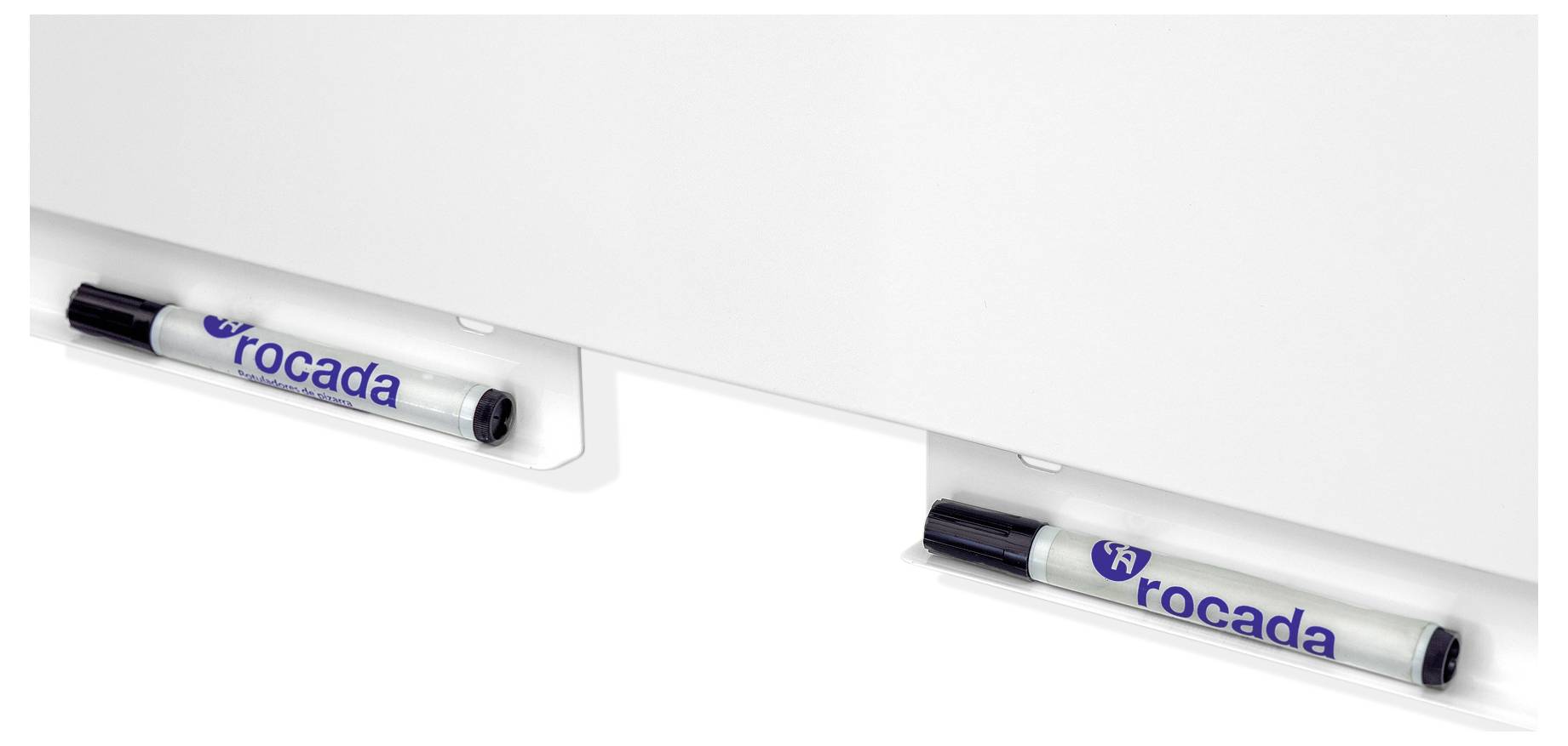 Dwa czarne długopisy z napisem 'rocada' wiszą na białym uchwycie do tablicy.