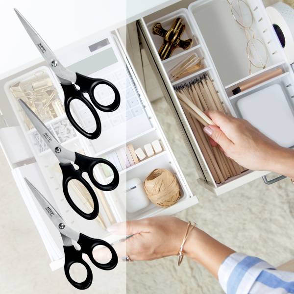 Szuflada biurka otwiera się, ukazując starannie ułożone artykuły biurowe, w tym nożyczki, długopisy, okulary i notes.