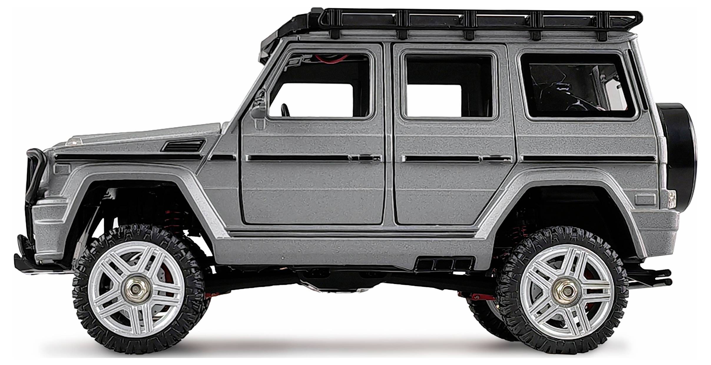 Srebrny samochód terenowy z czterema drzwiami, bagażnikiem dachowym i solidnymi oponami widziany jest z boku.