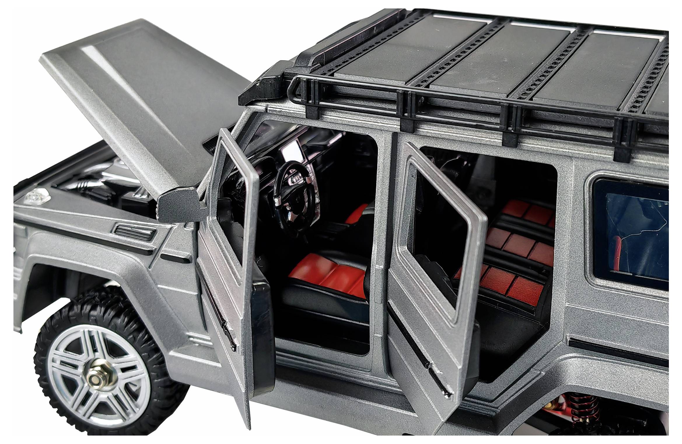 Srebrny model samochodu z otwartymi drzwiami i uniesioną maską silnika, widoczne czerwone siedzenia. Szczegółowe odwzorowanie samochodu terenowego.